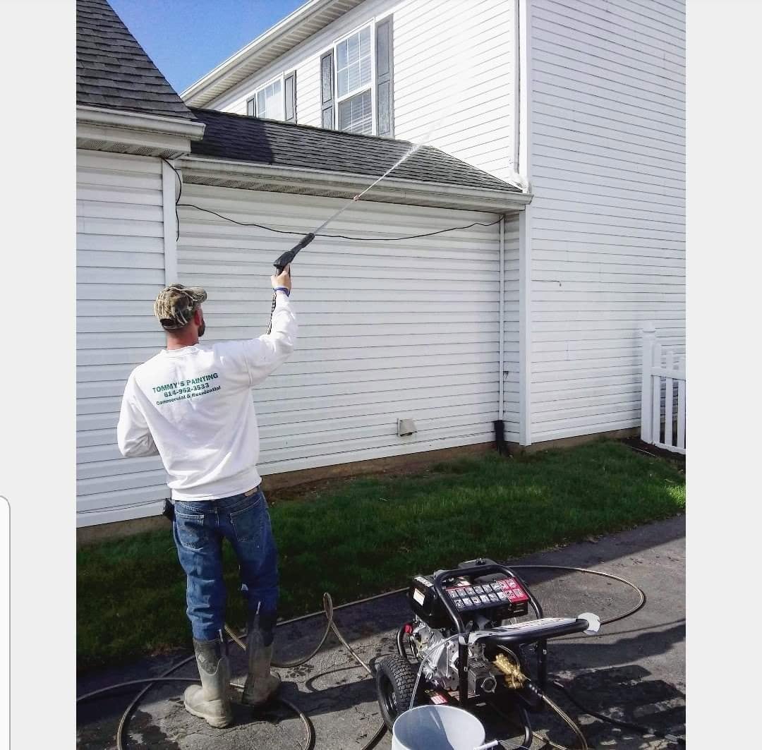 Flem Fam Services team member pressure washing a house exterior